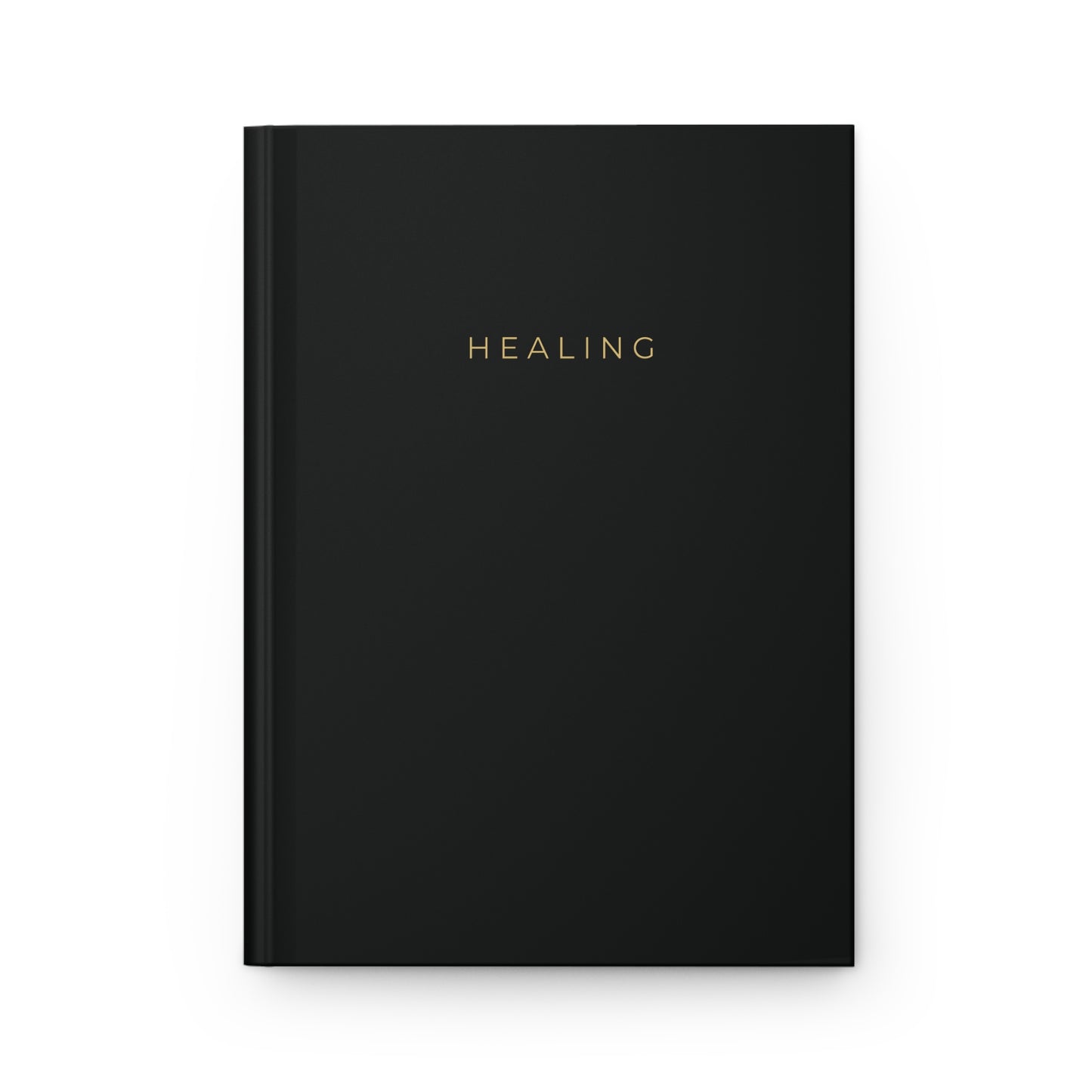 Black notebook with the word Healing written on the cover in gold. 